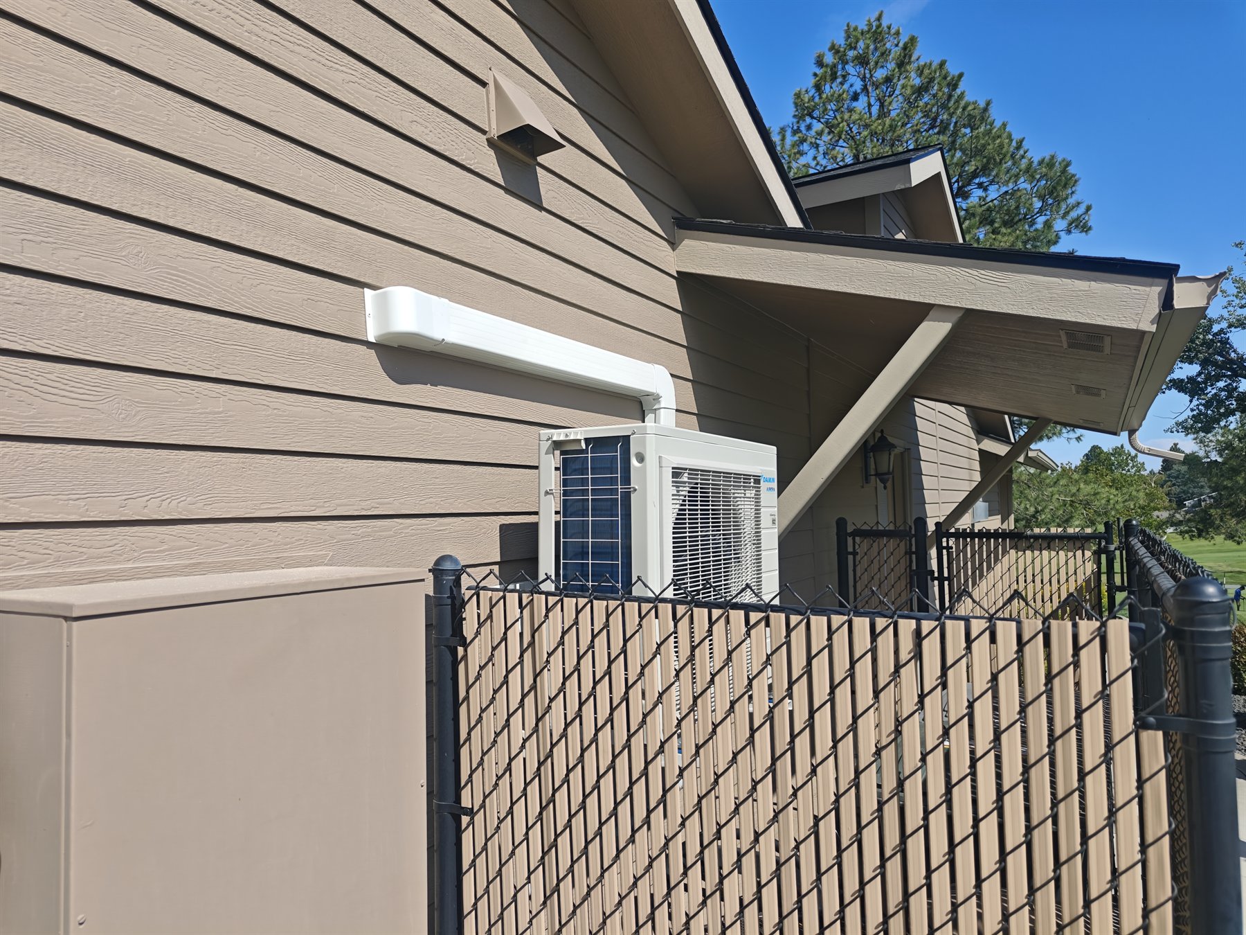 Finished wall-mounted Daikin mini-split condenser with line-hide routing on a residential exterior wall
